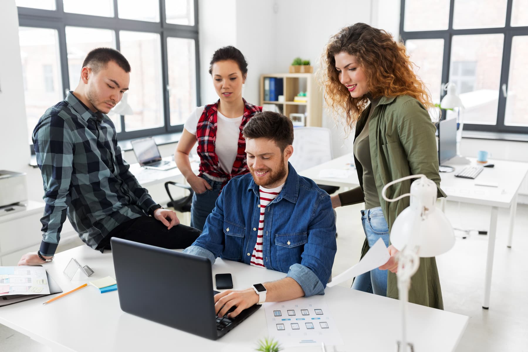 A team gathered around a laptop in an office
