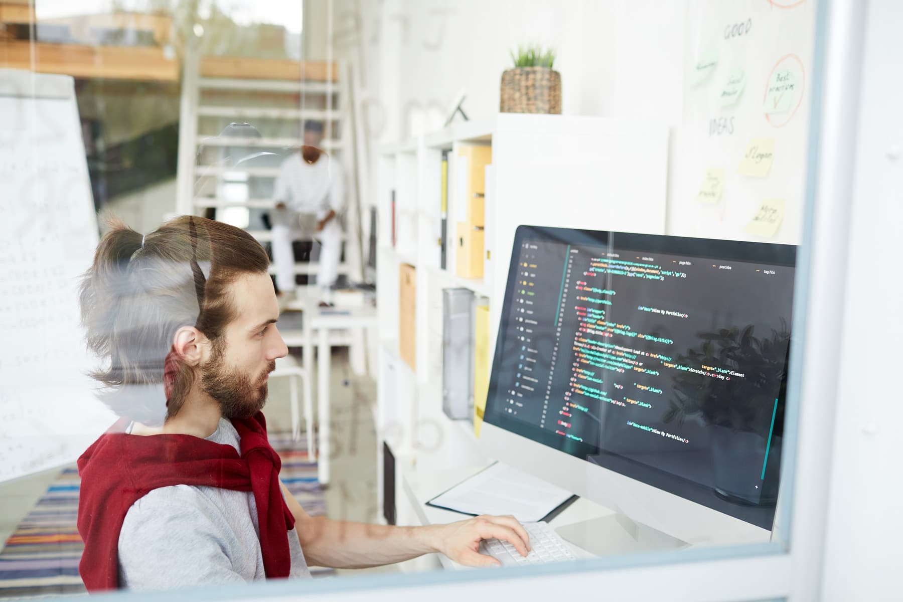 A person working at a monitor showing code